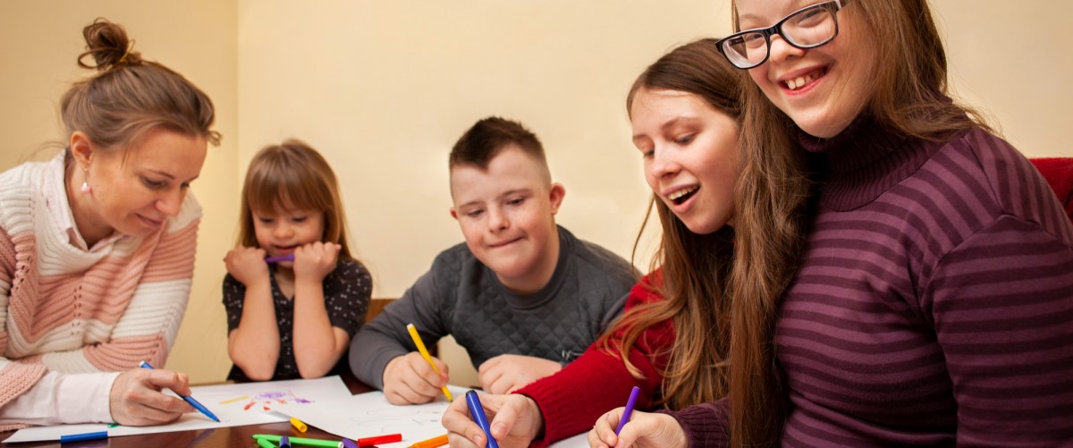 A mix of kids and grown-ups sitting at a table, learning and solving puzzles together.